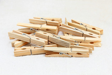 Wooden clothespins heap on white fabric.