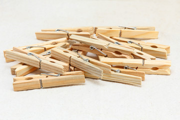 Wooden clothespins heap on white fabric background.