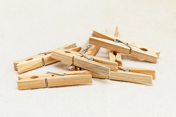 Heap of wooden clothespins on white fabric background.