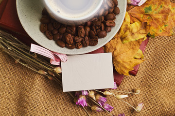 The cup of coffee lying on the books with maple leaves