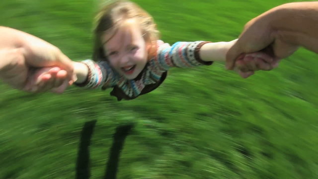 Point-of-view shot of a father spinning his young daughter around in their yard
