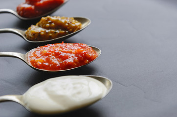 Different sauces and jams on spoons