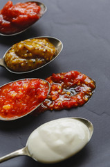Different sauces and jams on spoons