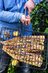 Hands holding a grill containing a barbequed fish
