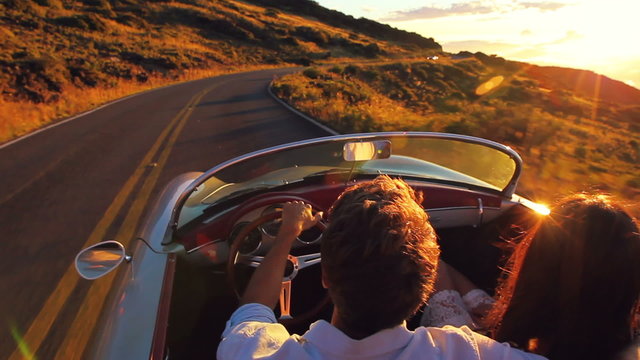 Romantic Freedom Love. Happy Couple Driving on Country Road into the Sunset in Classic Vintage Sports Car 