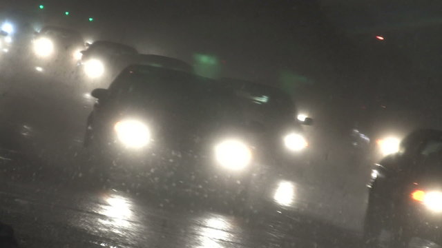 Canted angle of rush hour traffic coming home at night in a blizzard
