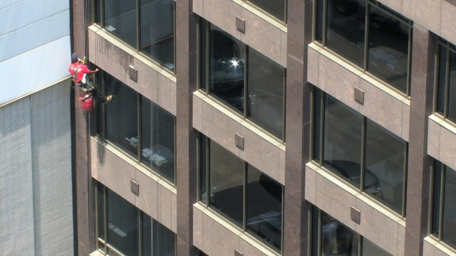 Time lapse, men wash windows on a skyscraper with cars from below in window reflection, high angle
