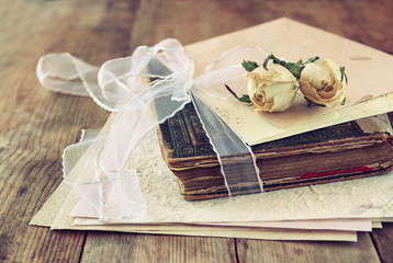 selective focus image of dry rose and old vintage books on wooden table