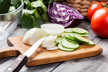 Chopped vegetables: onion and cucumber on cutting board