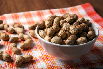 large grains of peanuts in the shell and the bowl