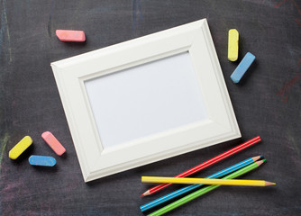 Photo frame and school supplies on blackboard background