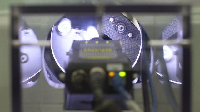 Two quality control shots in one: First, a camera inspects products as they move through the automated system. Then, a computer screen shows the software analyzing the images. 
