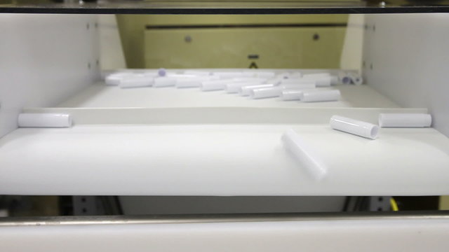 A conveyor belt drops plastic parts onto another conveyor in a factory
