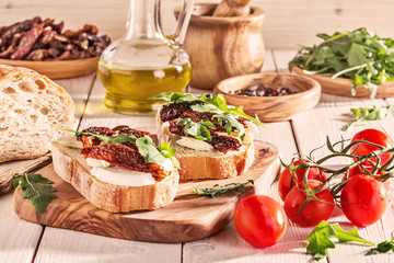 Sandwich with mozzarella, sun-dried tomatoes and arugula.
