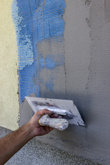 Spreading mortar on mesh of styrofoam insulation wall