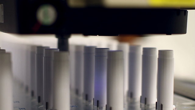 A wide angle and a close-up shot of an automated machine which uses cameras to perform product inspections at a microscopic level. 

