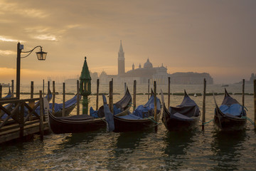 Gondolas by Saint Mark square during sunrise with San Giorgio di Maggiore church in the background in Venice Italy