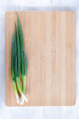 Overhead view of spring onion on wooden board, food background