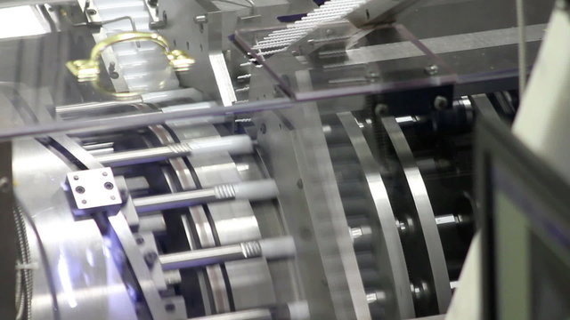 A machine assembles plastic parts into a chapstick housing in a factory
