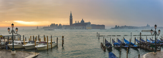 Fototapeta premium Gondolas by Saint Mark square during sunrise with San Giorgio di Maggiore church in the background in Venice Italy
