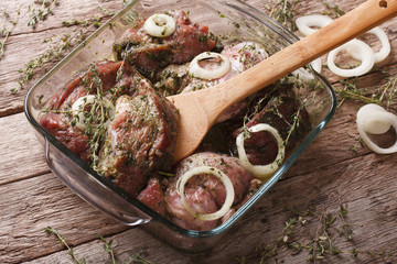 Raw meat in a green marinade with onions in a bowl closeup. horizontal
