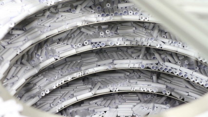 A conveyor system in a factory moves small plastic items (chap stick housing) upward to where they are sorted
