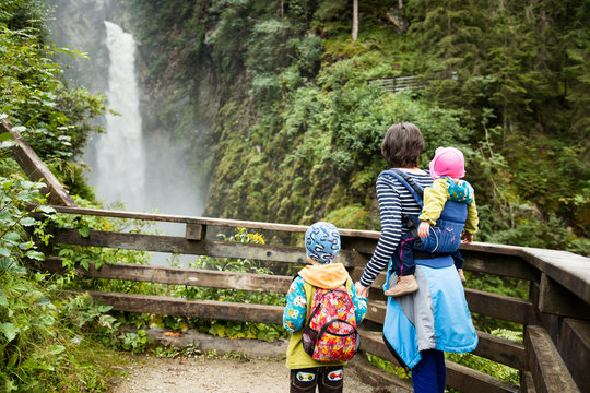 mother with children hiking near waterfall near krimm in austrian alps
