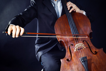 Fototapeta premium Man playing on cello on dark background