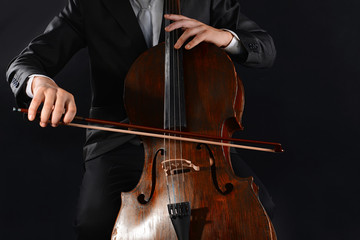 Fototapeta premium Professional cellist playing cello with bow, classical music performance and orchestral instrument artistry, the musician's hands are positioned on the strings and bow
