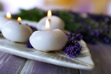 Fototapeta na wymiar Candles with lavender flowers on table close up