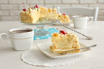 Peace of tasty Butter cake on plate, tea cups on color wooden background