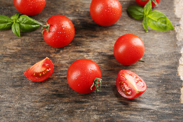 Cherry tomatoes with basil on wooden table close up