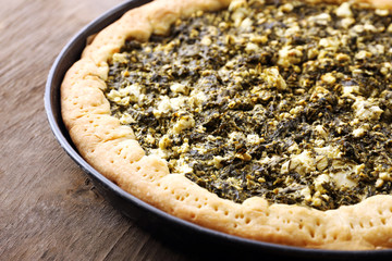 Open pie with spinach on wooden table close up