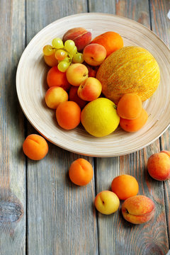 Heap of fresh fruits on tray on wooden table close up