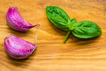 garlic cloves and basil leaves on wooden table background