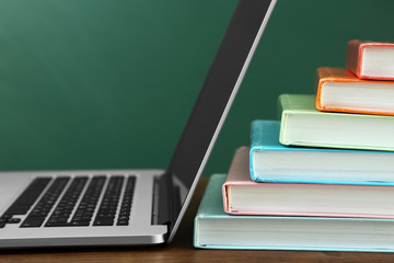 Stack of books with laptop on table in classroom