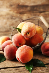 Ripe peaches in basket on wooden background