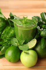 Green healthy juice with fruits and herbs on table close up