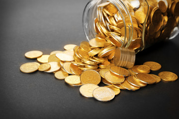 Glass jar with coins on dark background