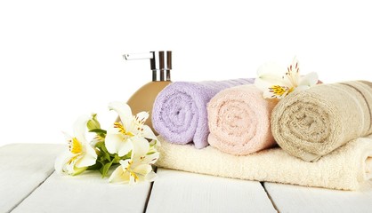 Obraz na płótnie Canvas Soft towels with dispenser and flowers isolated on white