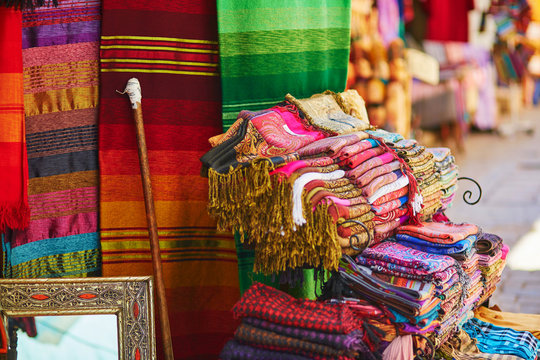 Colorful fabrics and carpets for sale on a street in Medina