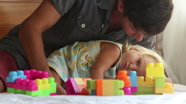 father plays with little daughter composing constructor kisses 