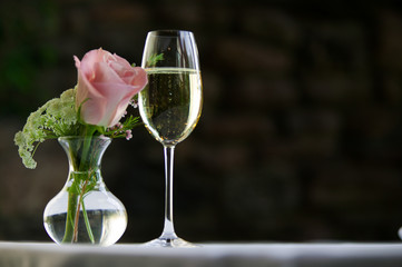 Pink rose with a glass of white wine.