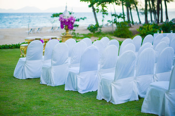 Rows of white covered chairs for asian buddhist wedding ceremony