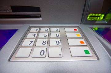 Close up of ATM keypad with withdrawal and card holes light on