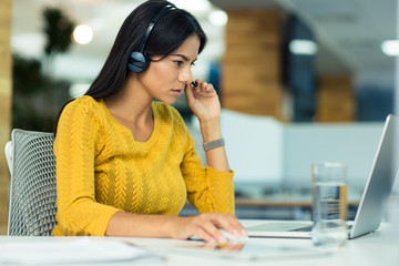 Businesswoman in headphones using laptop