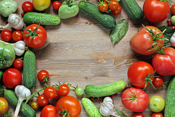 Fresh cucumbers, garlic, red and green tomatoes on a table.