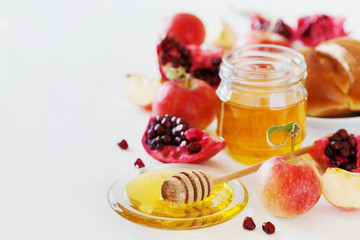 Honey, apple, pomegranate and hala, table set with traditional food for Jewish New Year Holiday, Rosh Hashana