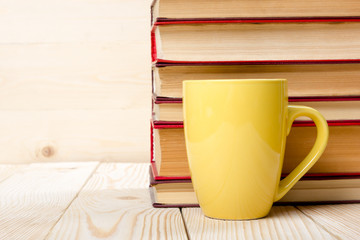 Stack of colorful books and cup on wooden table. Back to school. Copy space