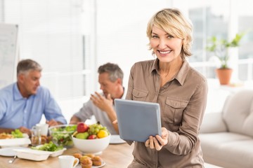Smiling casual businesswoman using tablet at lunch